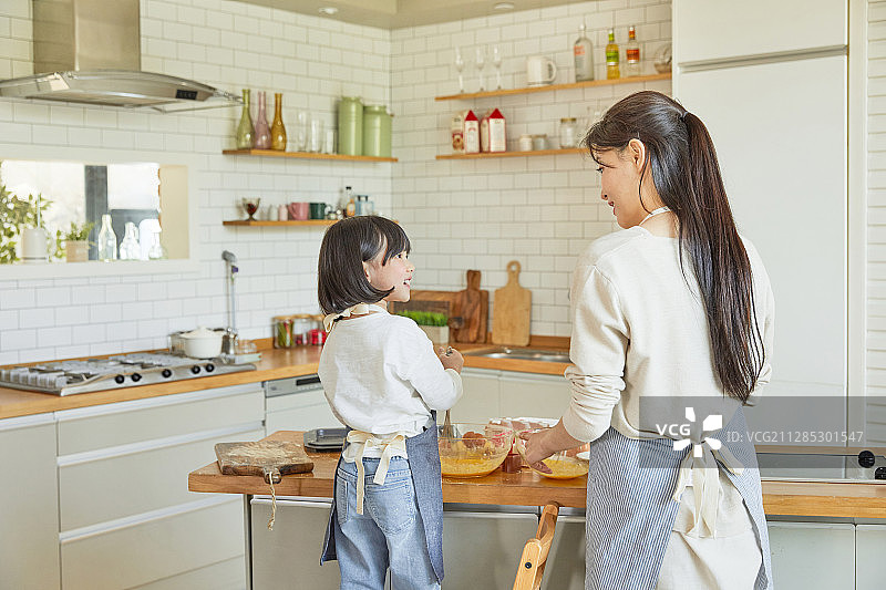 妈妈和女儿背影在厨房烹饪图片素材
