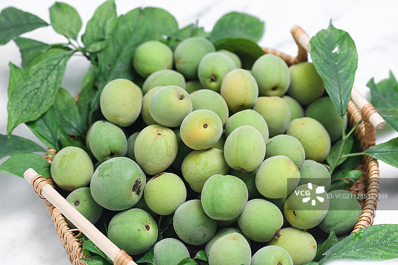 一筐新鲜的青梅放在白色背景上图片素材