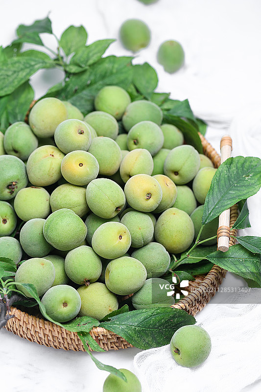 一筐青梅放在白色背景上图片素材