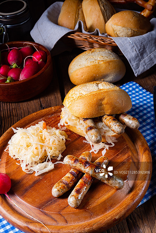 木板上搭配酸菜和面包卷的纽伦堡烤香肠图片素材