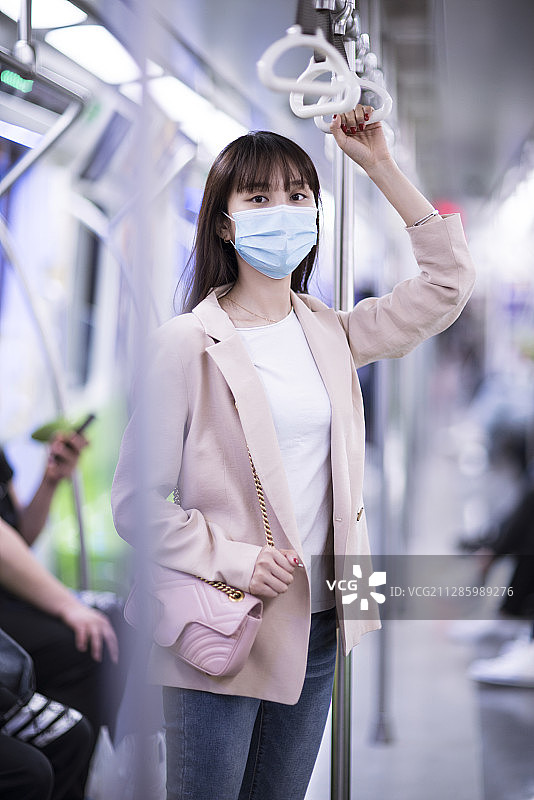 年轻女子戴着防护口罩乘坐地铁图片素材