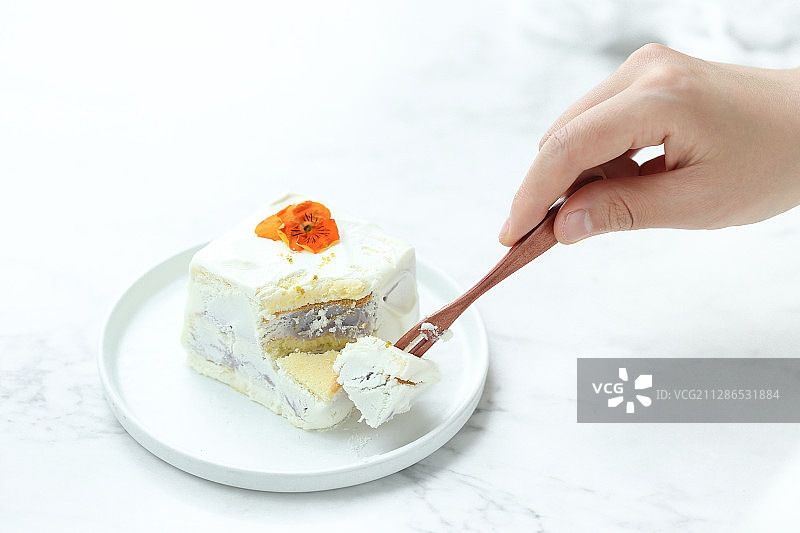 拿着叉子吃鲜花装饰的芋泥奶油蛋糕图片素材