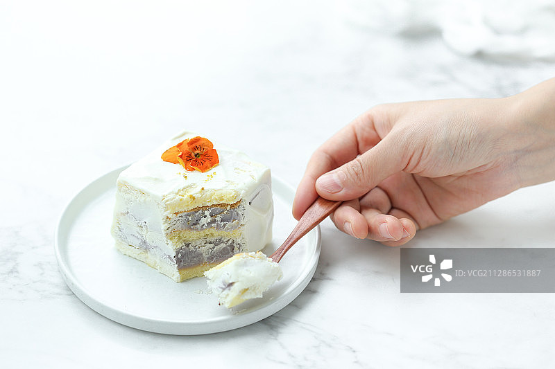 拿着叉子吃鲜花装饰的芋泥奶油蛋糕图片素材