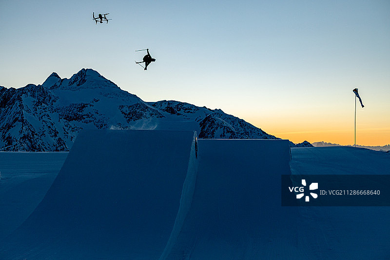 在奥地利山脉的早晨大跳台训练中无人机紧随滑雪者图片素材