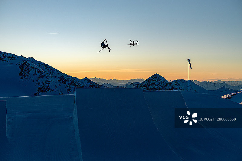 在欧洲举行的坡面障碍技巧世界杯训练期间，高空飞行的滑雪运动员和无人机图片素材