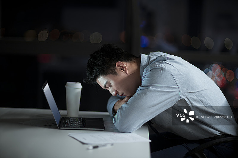 疲惫的男职员晚上在办公室加班图片素材