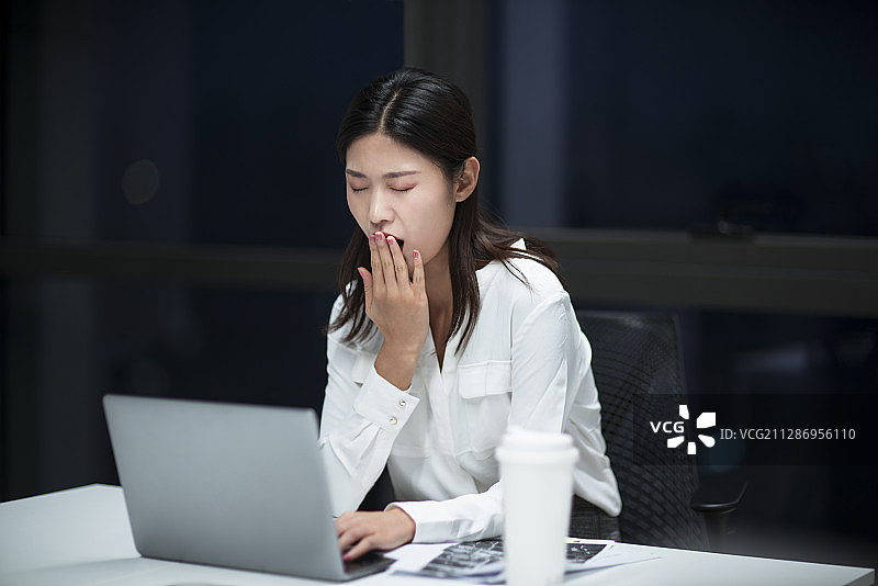 疲惫的女职员晚上在办公室加班图片素材