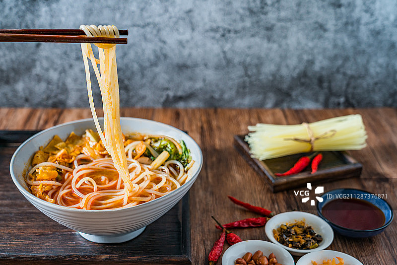 筷子夹起放在木桌上的螺蛳粉图片素材