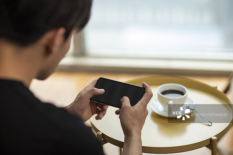 年轻男士在家玩手机游戏图片素材