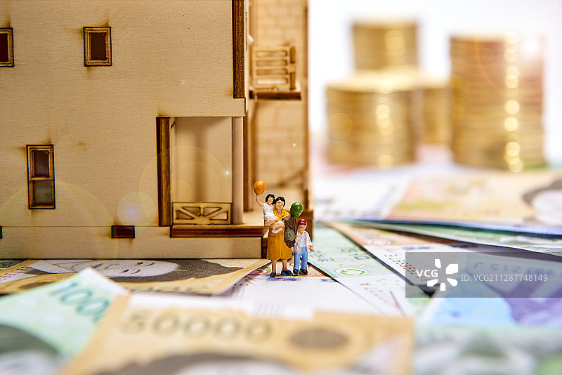 韩币堆上房屋模型旁的人物微缩景观摄影图片素材