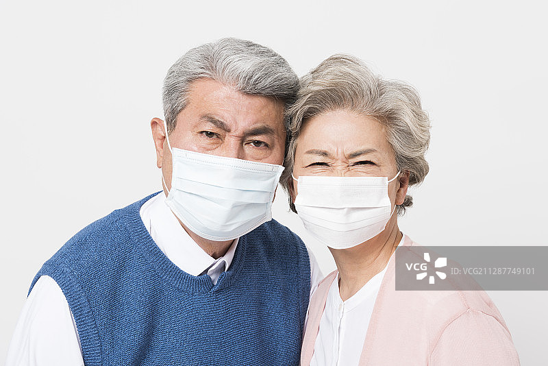 戴着口罩的老年夫妇皱着眉头，脸贴在一起的摄影照片图片素材