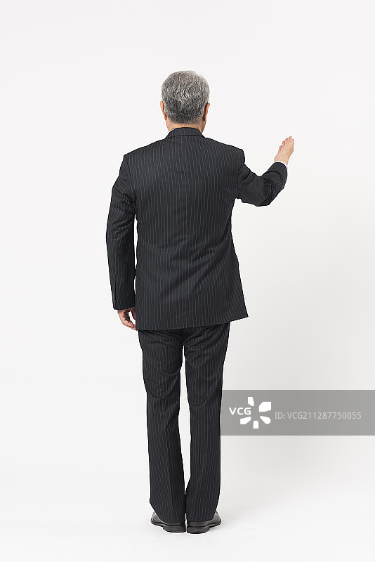身穿西装的老年男人回头做手势图片素材