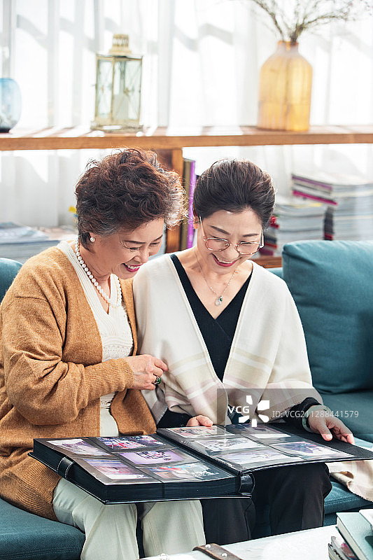 快乐的中老年姐妹坐在沙发上看相册图片素材