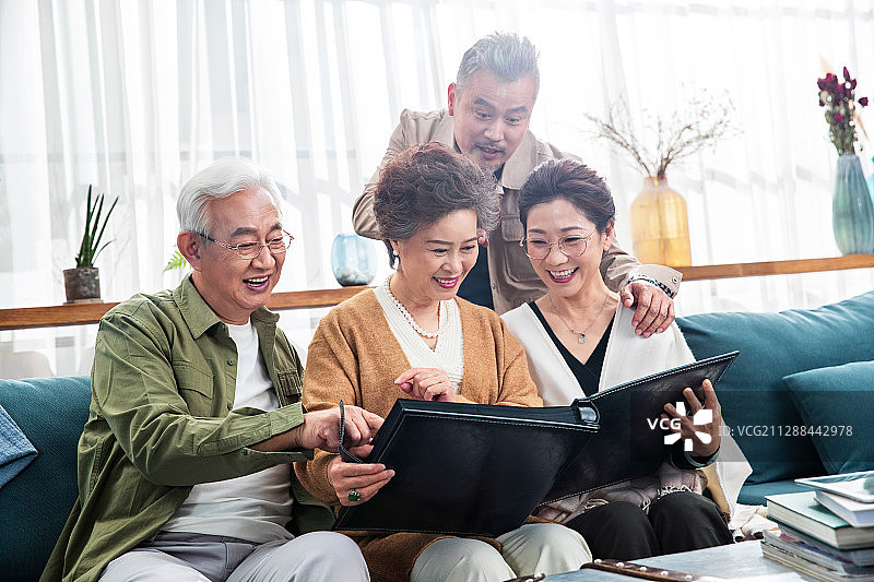 中老年朋友坐在沙发上看相册回忆从前图片素材