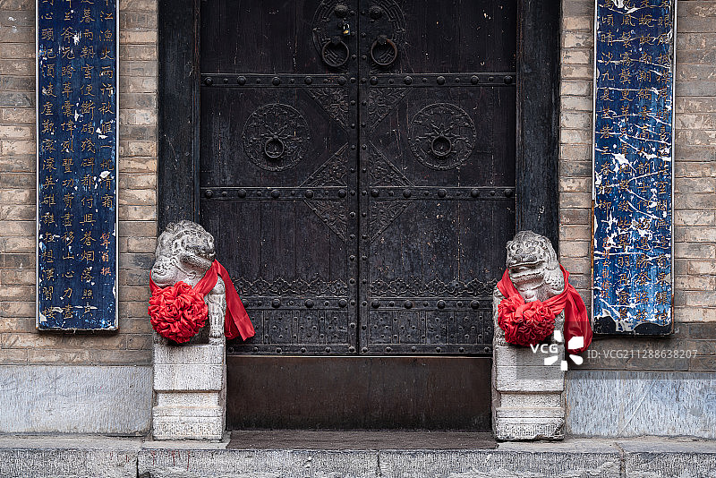 中国陕西省西安市小巷门前一对扎红绣球的石狮子图片素材