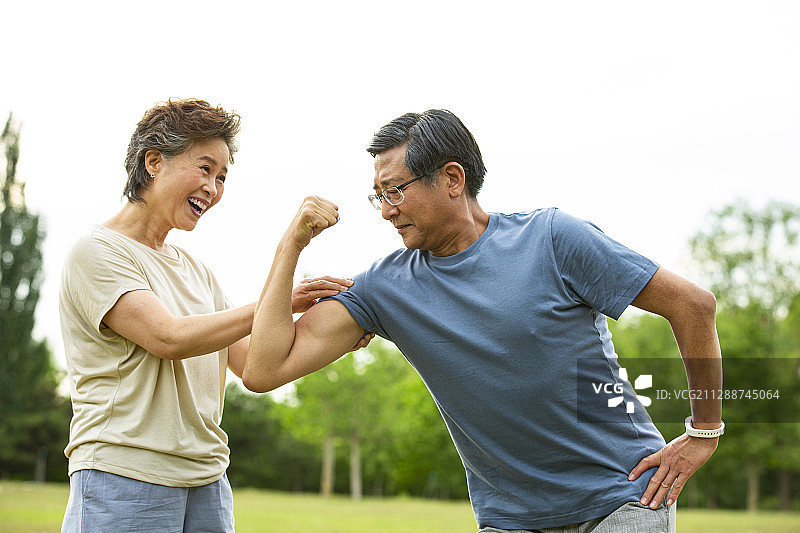 老年男人向老年女人展示肌肉在户外公园运动后图片素材
