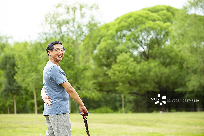 男老人拿着拐棍公园草地散步图片素材