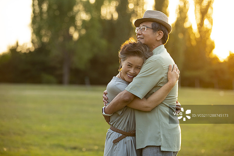 夕阳下老年伴侣在户外约会拥抱图片素材