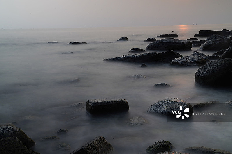 海上落日 清晰的礁石，落日的余晖水面上，也映在礁石的，慢门让图片素材