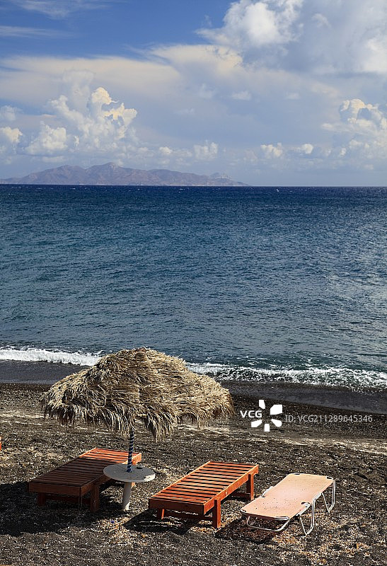圣托里尼火山地质黑色沙滩上的太阳伞及躺椅图片素材