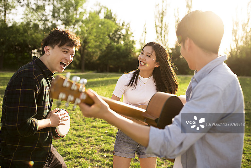 年轻朋友在户外草地表演音乐图片素材