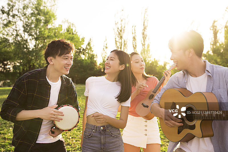 年轻朋友在户外草地唱歌演奏音乐图片素材