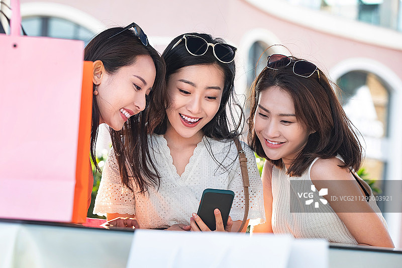 坐在路旁咖啡店休息玩手机的年轻女孩图片素材