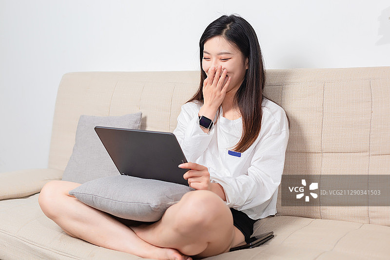 坐在沙发上的美女，正在使用平板电脑图片素材