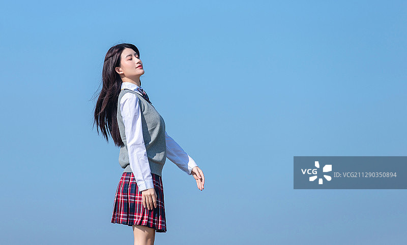 蓝色天空背景下的亚洲女学生图片素材
