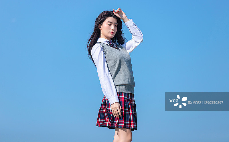 蓝色天空背景下的亚洲女学生图片素材