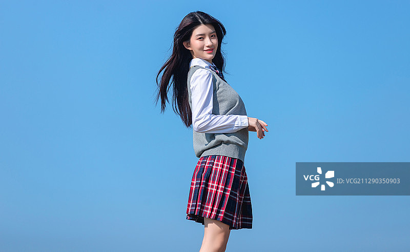 蓝色天空背景下的亚洲女学生图片素材