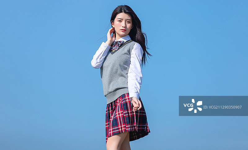 蓝色天空背景下的亚洲女学生图片素材