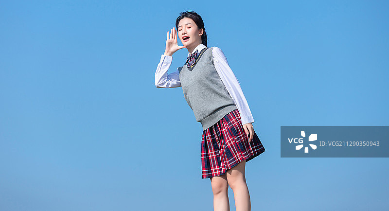 蓝色天空背景下，正在呐喊的亚洲女学生图片素材