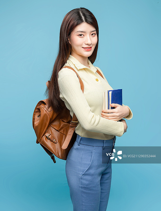 蓝色背景里，背着书包的亚洲美女图片素材