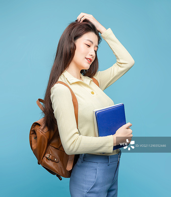 蓝色背景里，背着书包的亚洲美女图片素材