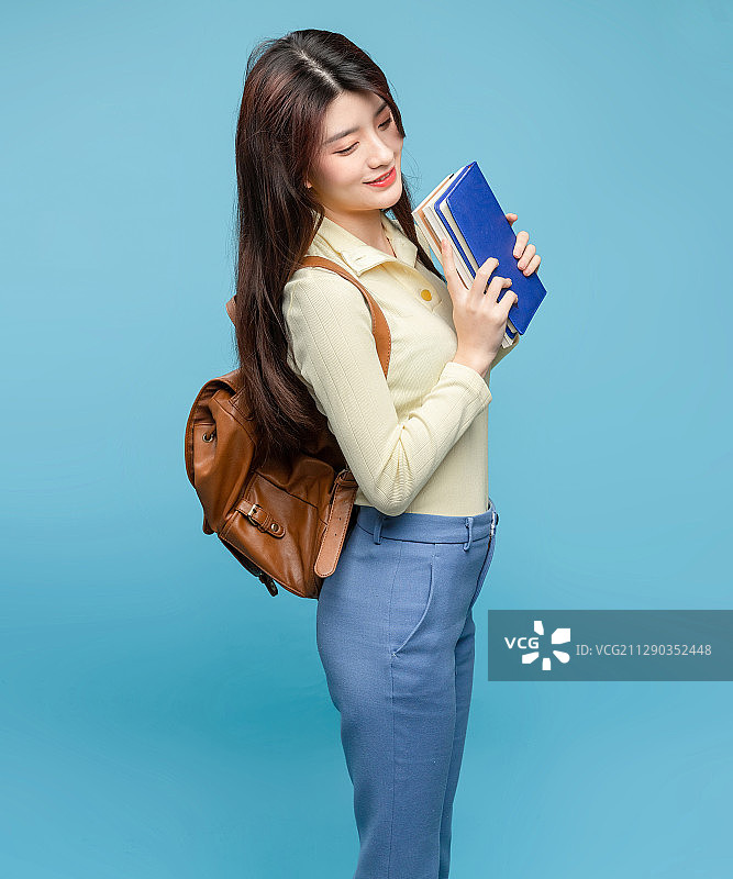 蓝色背景里，背着书包的亚洲美女图片素材