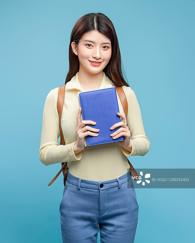 蓝色背景里，背着书包的亚洲美女图片素材