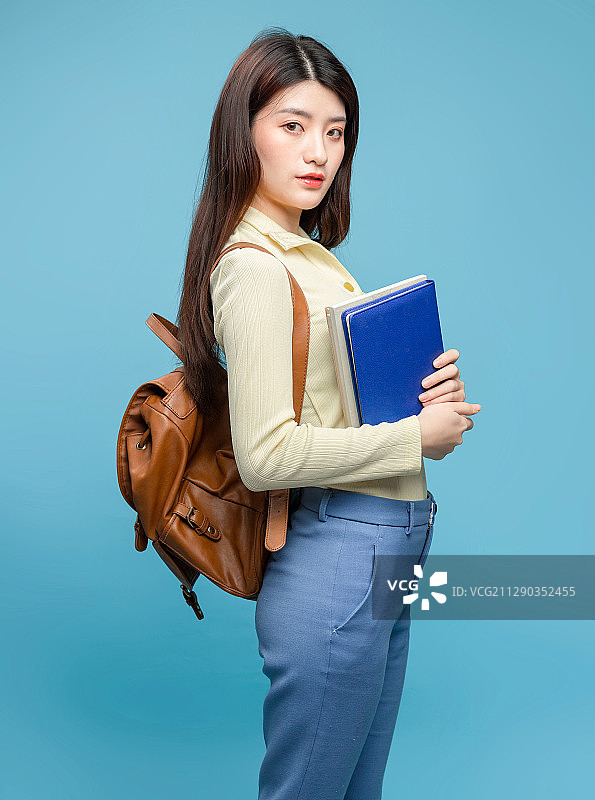 蓝色背景里，背着书包的亚洲美女图片素材