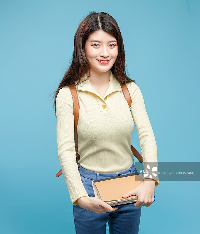 蓝色背景里，背着书包的亚洲美女图片素材