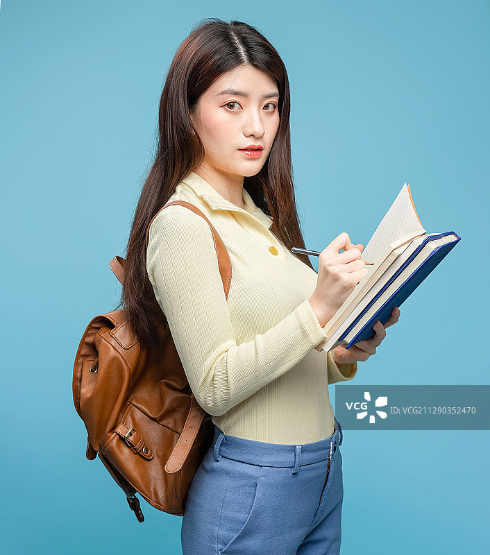蓝色背景里，背着书包的亚洲美女图片素材