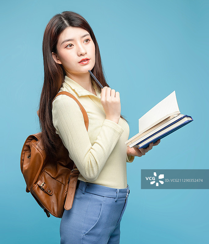 蓝色背景里，背着书包的亚洲美女图片素材