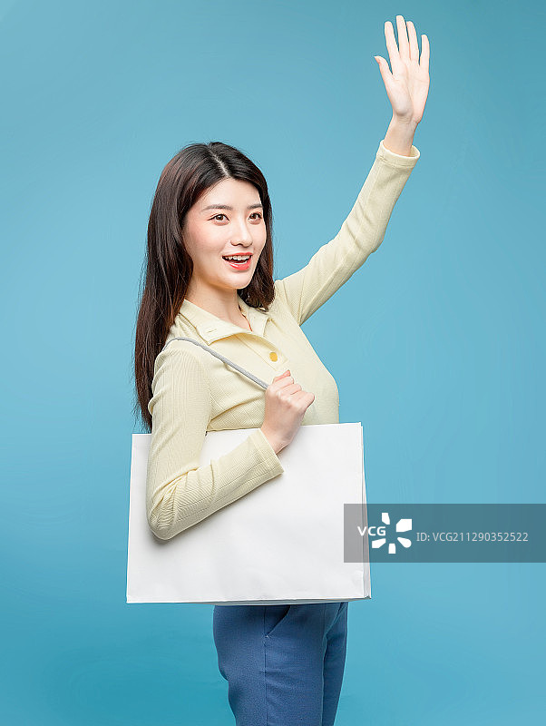 蓝色背景里，拿着购物袋的亚洲美女图片素材