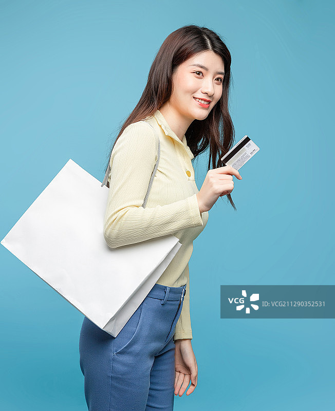 蓝色背景里，拿着购物袋的亚洲美女图片素材