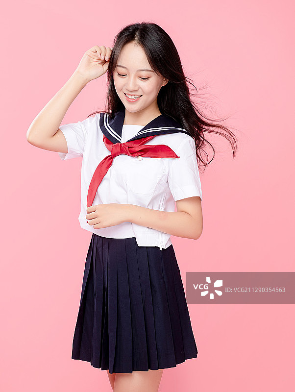 粉红色背景里，头发飘逸的可爱女学生图片素材