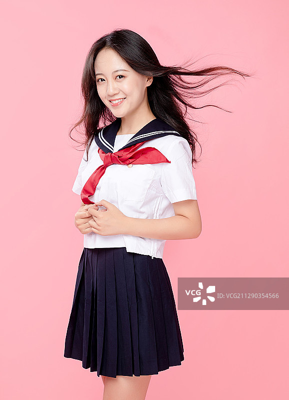粉红色背景里，头发飘逸的可爱女学生图片素材