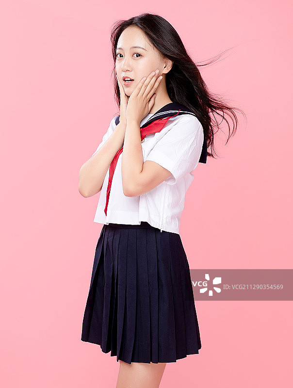 粉红色背景里，头发飘逸的可爱女学生图片素材