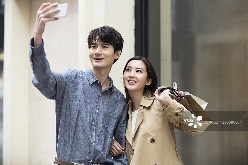 快乐的年轻情侣用手机自拍图片素材