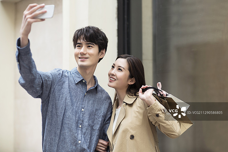 快乐的年轻情侣用手机自拍图片素材