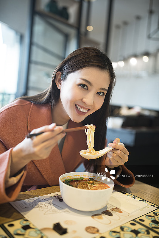 年轻女子在餐厅吃面条图片素材
