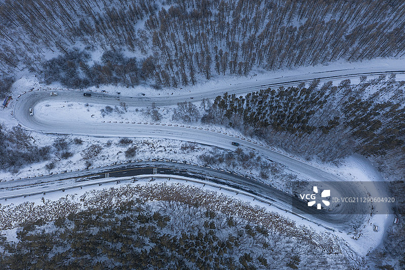 航拍雪地上和森林旁的弯曲的道路图片素材